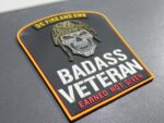 Veterans Day 2025 DCFD Badass Veteran PVC patch collection with glow-in-the-dark text featuring tactical skull design and American flag background with saluting soldiers silhouette