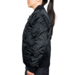 Woman wearing a navy blue 1221-JW Bravest Ladies Fit Quilted Jacket with ribbed collar and cuffs, designed for female first responders.