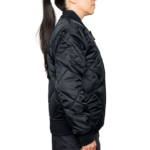 Woman wearing a navy blue 1221-JW Bravest Ladies Fit Quilted Jacket with ribbed collar and cuffs, designed for female first responders.